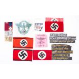 A collection of German NSDAP arm bands together with a group of hat talies and metal vesta cases.