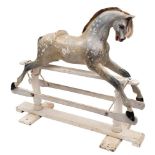 A late 19th/early century painted pine rocking horse: glass eyes, open mouth with teeth,