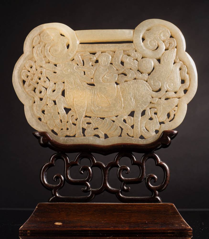 A large Chinese jade plaque in the form of a lock: carved and pierced to one side with a diety