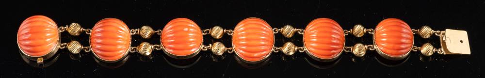 A mid-20th century coral bracelet,: the carved oval shaped coral with reeded beads in between,