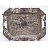 An Oriental silver tray: of rectangular outline with embossed decoration of buildings amongst trees,