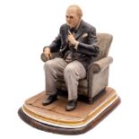 A Capo-di-Monte porcelain figure of Winston Churchill: seated in an armchair with cigar in hand,