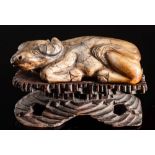 A Chinese carved soapstone model of a reclining bullock: 8cm long, mounted on a wood stand.
