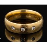 An 18 carat gold and diamond ring,: the polished band set with three brilliant cut diamonds,