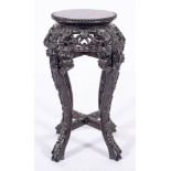 A Chinese carved and stained hardwood stand, late 19th century,: the circular top with beaded edge,