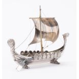 A continental white metal model of a Viking longship: set sail over carved bow and stern uprights