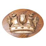 A Royal Navy brass crown tompion: later mounted on an elm oval plinth, 28 x 38cm.