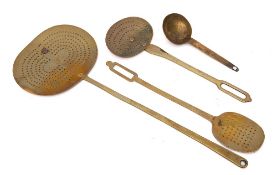 A 19th Century brass oval long handled skimmer:, a smaller oval skimmer and one other,