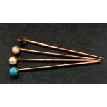 Four gemset stick pins,: respectively set with a cabochon-cut 'angel hair' coral, a seed pearl,