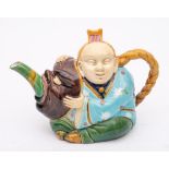 A Minton majolica 'Chinaman' teapot and cover: modelled seated in robes holding a large theatrical