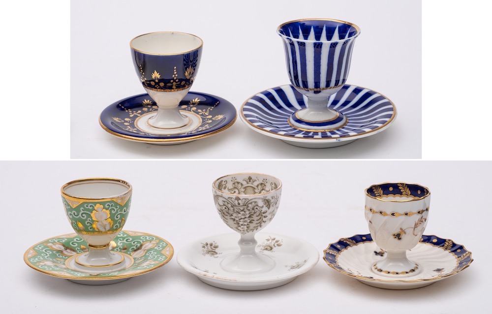 A group of five egg cups on integral stands: including a Chamberlains Worcester cup with blue