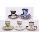 A group of five egg cups on integral stands: including a Chamberlains Worcester cup with blue