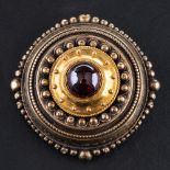 A 15ct gold, late Victorian, Etruscan Revival style, cabochon-cut garnet brooch,: diameter ca. 3.
