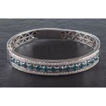 A hinged gold bangle with treated blue, round, brilliant-cut diamonds and white, round,