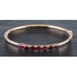 A 9ct gold bangle set with oval-shaped, mixed-cut garnets:, calculated total garnet weight ca. 2.