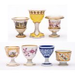 A group of seven egg cups: including a campana-shaped cup painted with a rustic landscape,