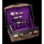 A leather travelling vanity case: fitted with silver mounted bottles, hairbrushes,