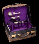 A leather travelling vanity case: fitted with silver mounted bottles, hairbrushes,