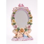 A Plaue en Havel porcelain mirror: of oval flower encrusted form with ribbon cresting supported on