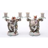 A pair of Sitzendorf porcelain two branch figural candelabra: each modelled as humorous musicians