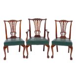 A set of seven mahogany and green leather upholstered dining chairs in George III style,