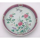 A Chinese famille rose charger: enamelled with two birds flying amongst peony branches issuing from