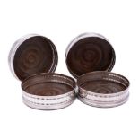 A set of four silver plated wine coasters: of circular outline,