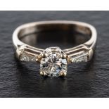 A round, brilliant and tapered baguette-cut diamond three stone ring,