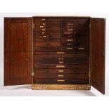 An overpainted pine tool/collectors cabinet: the double panel doors enclosing an array of 28 short