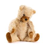 A blonde plush Teddy bear: glass eyes, stitched nose and mouth, brown plush pads and growler,