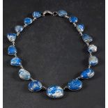 A graduated lapis lazuli pebble mounted necklace: with spectacle frame settings, length ca.