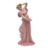 A large early Royal Doulton figure: of a girl dancer with elaborate ribbon and floral headdress,