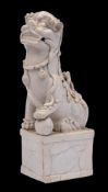 A Chinese blanc-de-chine Buddhist lion dog: on raised rectangular plinth,