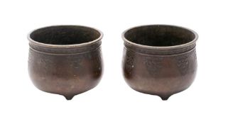 A pair of Chinese bronze censers: of circular form with banded decoration to the rim and raised on