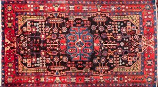 A Nahawand rug:, the shaded field with a central pastel blue brick red and rose medallion,