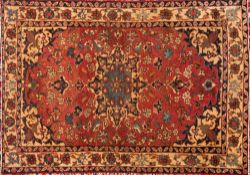 An Isfahan rug:, the rose cartouche field with a central beige,