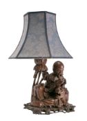 A Chinese carved hardwood table lamp: depicting an Immortal seated with a tiger and reading a book,