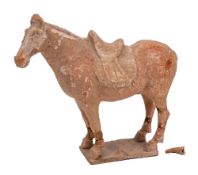 A Chinese terracotta figure of a caparisoned horse: standing four-square and decorated with traces