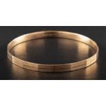 A 9ct gold bangle with engine-turned decoration,: with hallmarks for Birmingham, 1930,