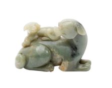 A Chinese celadon jade carving: of a reclining dog with a puppy on it's back, the stone with cream,