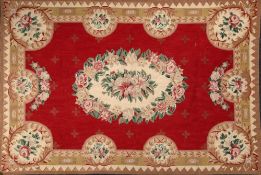 An Aubusson style flat weave panel: the wine red field with central floral medallion,