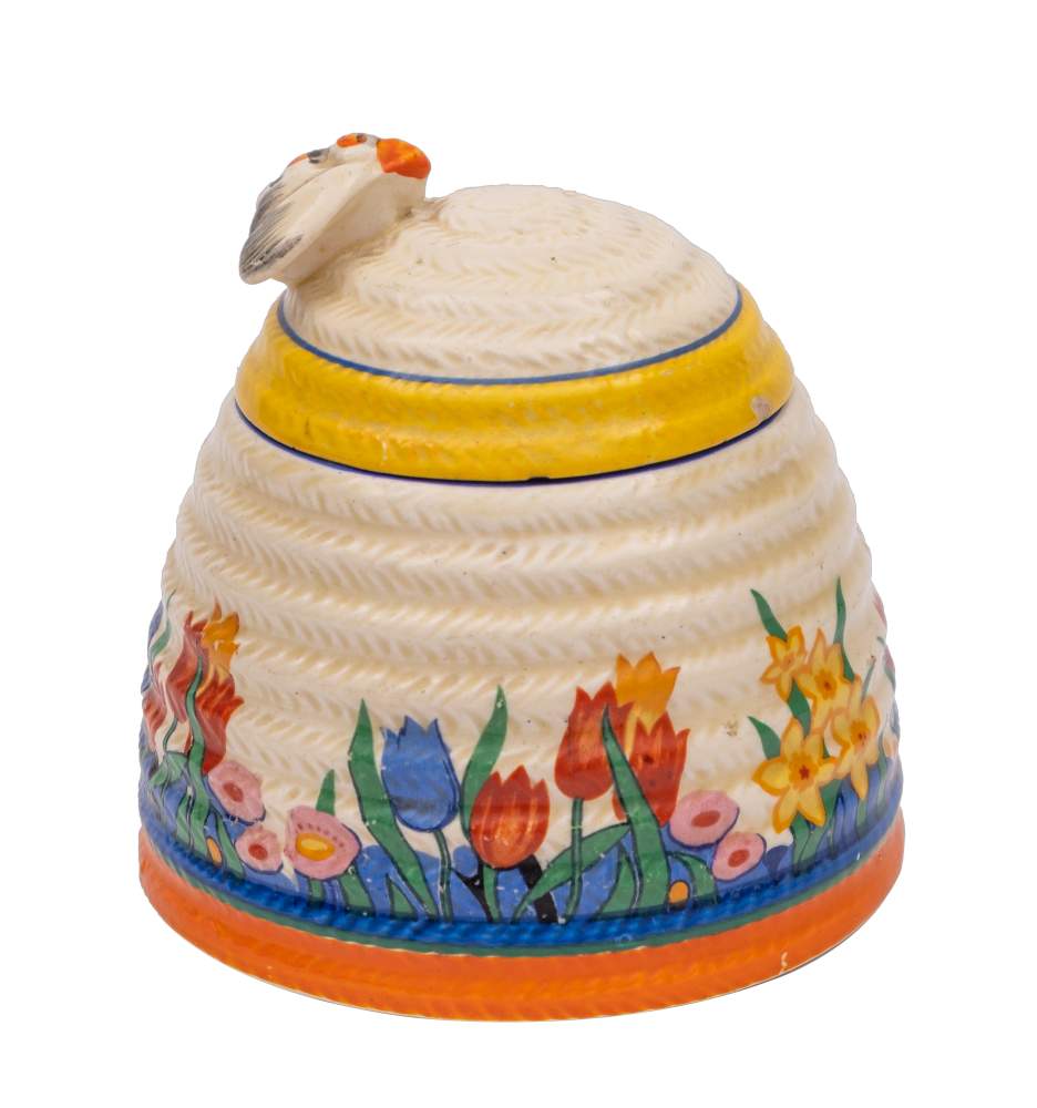 A Clarice Cliff beehive honey pot and cover: of ribbed form, the cover with bee finial,