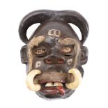 A Congolese tribal mask with painted face and tusks with applied eyebrows and moustache, 33cm high.