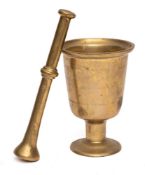 A brass mortar: of chalice shape, on circular foot, 21cm high, together with a brass pestle.