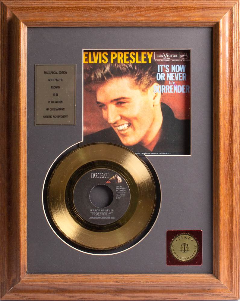 Elvis Presley. A gold plated 45rpm single 'It's Now or Never'; framed and glazed, 40 x 29cm.