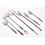 A collection of four three pronged toasting forks: of various designs.