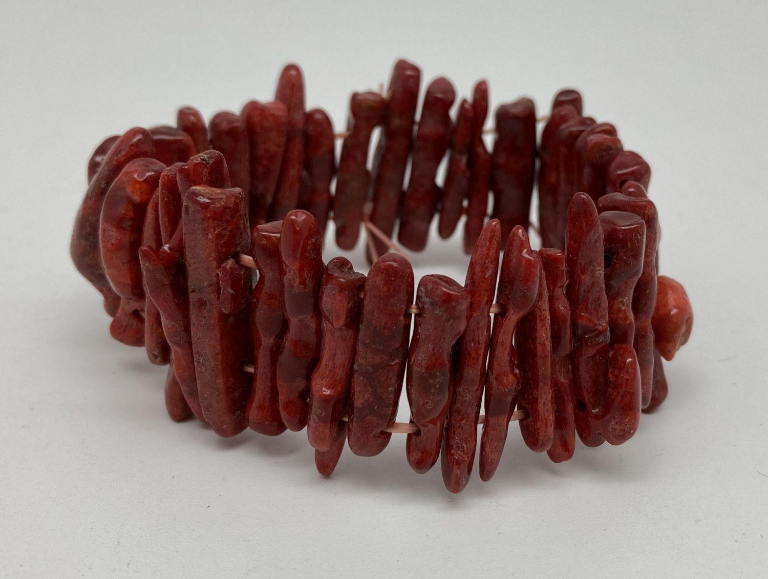 A costume jewellery elasticated bracelet made from long pieces of stem coral in a deep red/brown