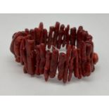 A costume jewellery elasticated bracelet made from long pieces of stem coral in a deep red/brown