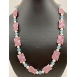 A 22" fresh water pearl necklace with pink jade curved square shaped beads & gold tone hook clasp.