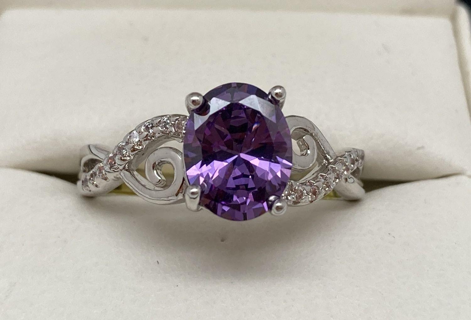 A rhodium plated Swarovski crystal set costume jewellery dress ring. Central oval cut purple crystal